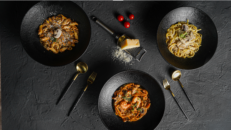 Overhead food photography of pasta dishes on a dark table